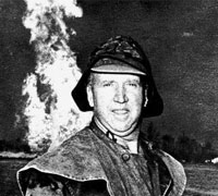 Myron Kinley standing in front of a oil fire.
