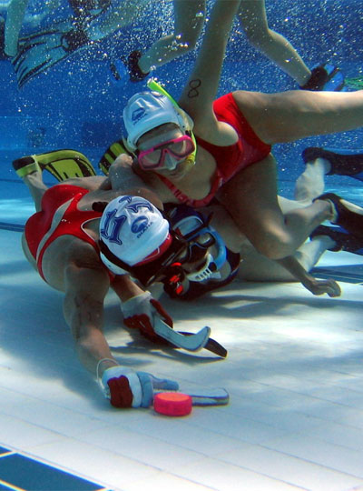 Two underwater hockey players struggle for pocession of the puck