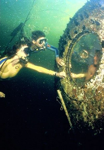 Two divers exchanging glances with guest at Jules' Undersea Lodge