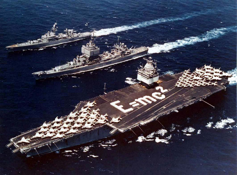 Three nuclear powered ships, (top to bottom) nuclear cruisers USS Bainbridge and USS Long Beach with USS Enterprise the first nuclear powered aircraft carrier in 1964. Crew members are spelling out Einstein's mass-energy equivalence formula E=mc2 on the flight deck.